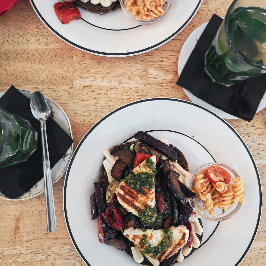 Overhead view of a brunch table with plates of food and an iced green drink on a wooden table